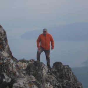 Константин Мышкин стоит на краю обрыва (2033). Вершина горы Афон